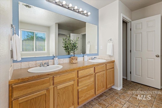 bathroom featuring a sink, visible vents, baseboards, and double vanity