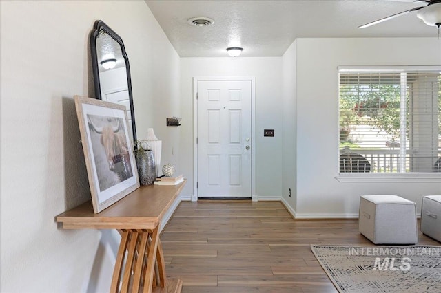 foyer with visible vents, ceiling fan, baseboards, wood finished floors, and a textured ceiling