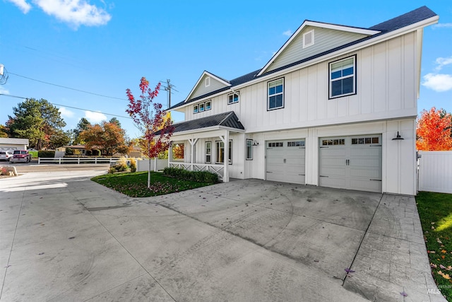 traditional-style house featuring driveway, board and batten siding, an attached garage, metal roof, and fence