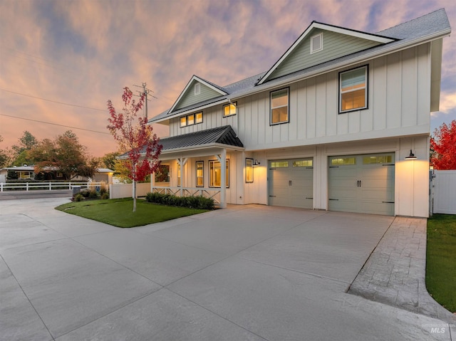 view of front of property featuring driveway, board and batten siding, a front yard, a standing seam roof, and fence