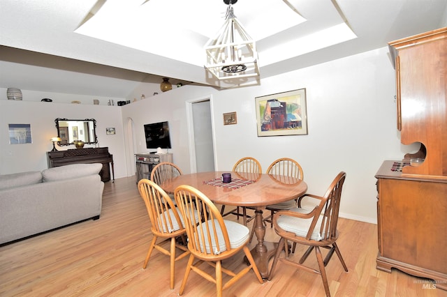 dining area featuring a chandelier, light hardwood / wood-style floors, and a skylight