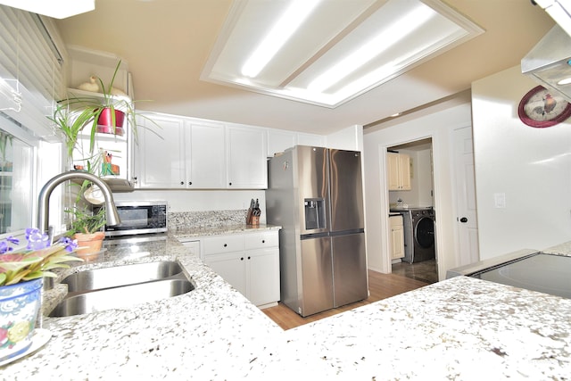 kitchen featuring sink, white cabinetry, stainless steel fridge with ice dispenser, light hardwood / wood-style flooring, and washer / clothes dryer