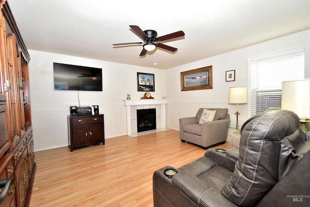 living room featuring ceiling fan, a fireplace, and light wood-type flooring