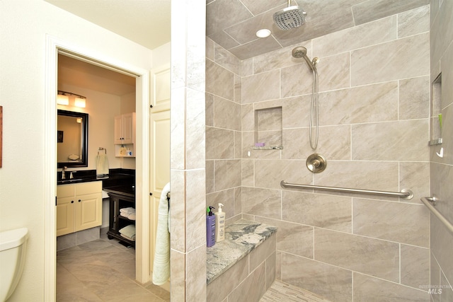 bathroom featuring a tile shower, vanity, and toilet