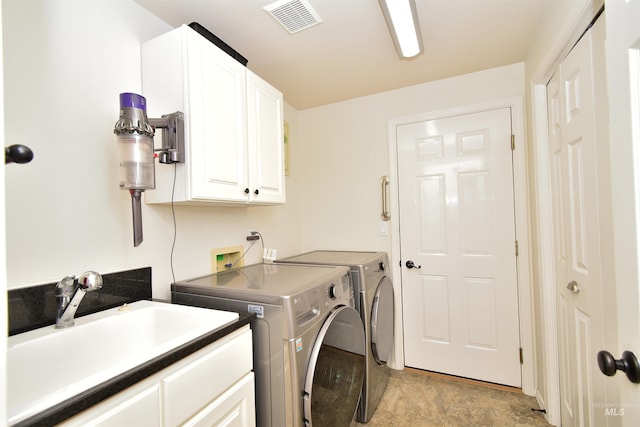 clothes washing area featuring cabinets, sink, and washer and dryer