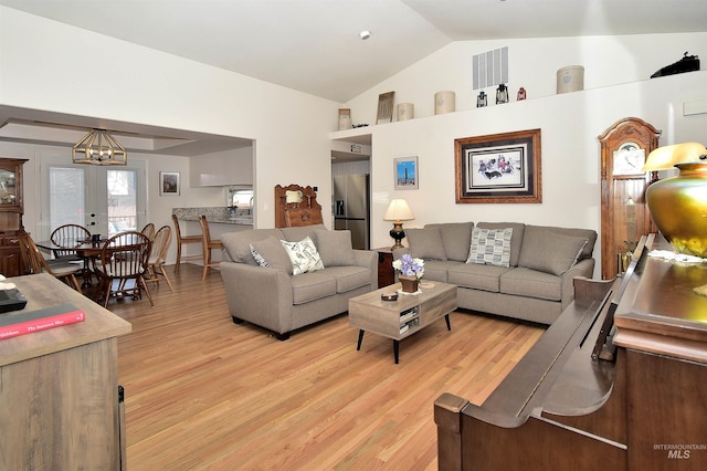 living room with lofted ceiling, light wood-type flooring, and french doors