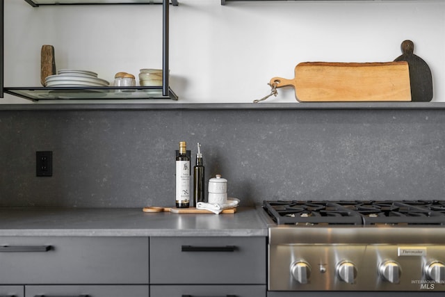 kitchen featuring gray cabinets, stainless steel stove, and backsplash