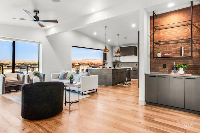 living room with lofted ceiling, ceiling fan, and light wood-type flooring