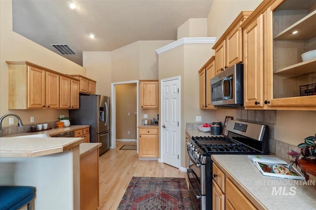 kitchen featuring light brown cabinetry, a sink, light wood-style floors, stainless steel appliances, and visible vents