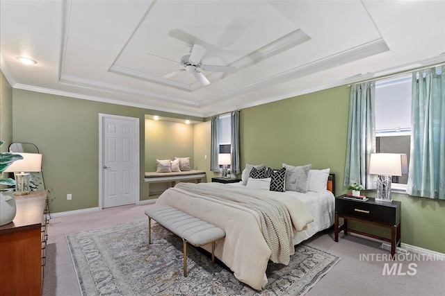 bedroom with carpet flooring, crown molding, baseboards, and a raised ceiling