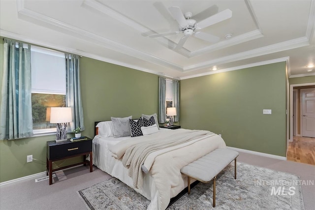 bedroom with a ceiling fan, crown molding, baseboards, carpet, and a tray ceiling