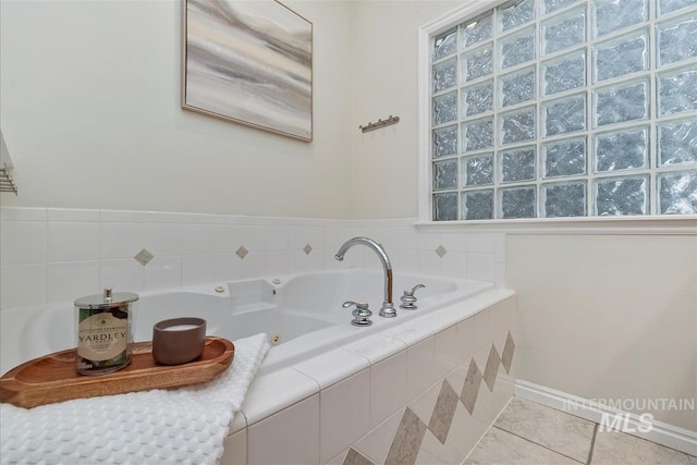 bathroom featuring a tub with jets, baseboards, and tile patterned floors