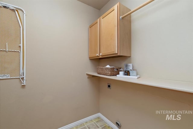 clothes washing area with baseboards, electric dryer hookup, and cabinet space