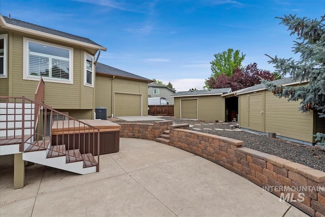 view of patio with a storage unit, a hot tub, central AC, and an outbuilding