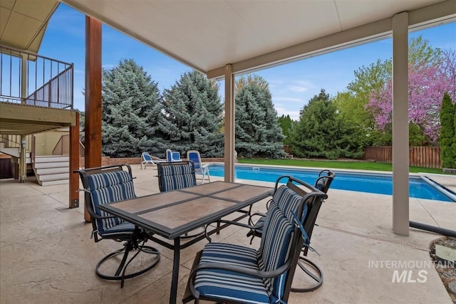 view of patio featuring fence, outdoor dining area, stairs, and an outdoor pool