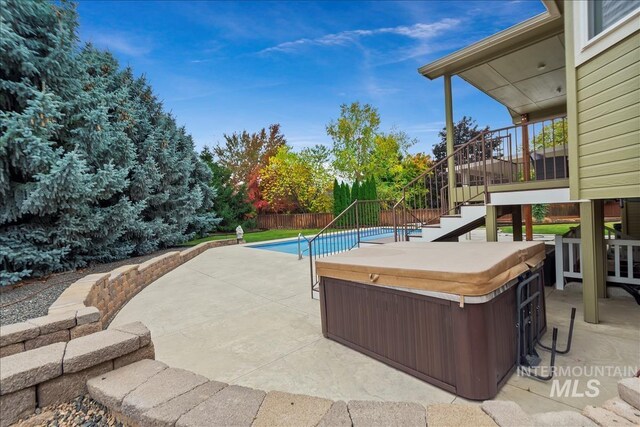 view of swimming pool with stairway, a hot tub, a fenced in pool, fence, and a patio