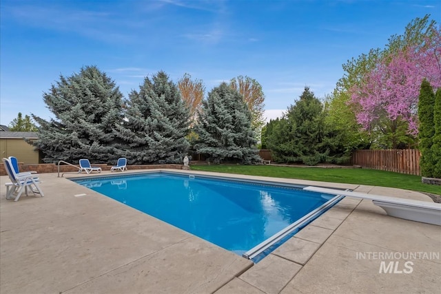 view of swimming pool with fence, a diving board, a fenced in pool, a patio area, and a lawn