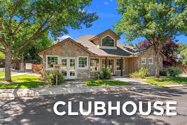 bungalow-style house featuring fence, a shingled roof, french doors, and stone siding