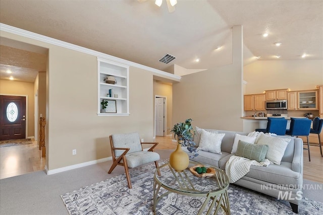 living room with light colored carpet, visible vents, built in shelves, baseboards, and lofted ceiling