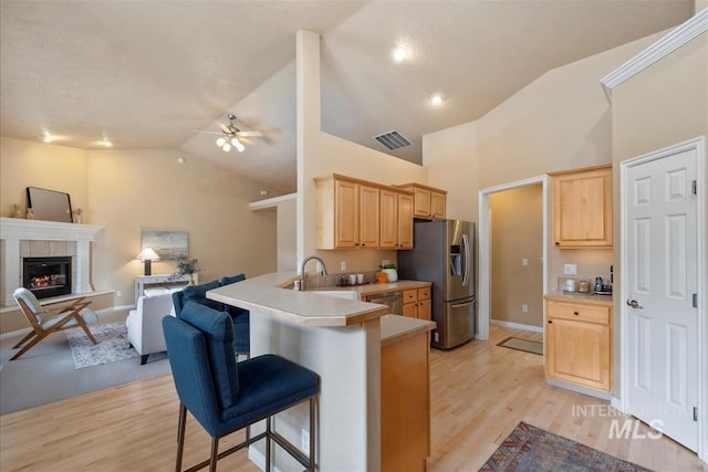 kitchen with light brown cabinets, a kitchen breakfast bar, stainless steel appliances, open floor plan, and visible vents