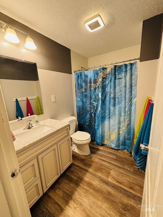 802 S 9th St, Rupert, ID 83350 - full bath with wood finished floors, a textured ceiling, vanity, toilet, and a textured wall