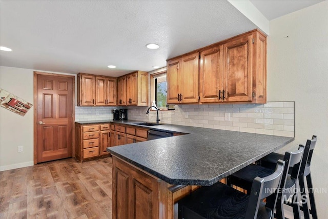76 W Castle Creek Rd, Garden Valley, ID 83622 - kitchen featuring dark countertops, brown cabinetry, a sink, light wood-type flooring, and a breakfast bar