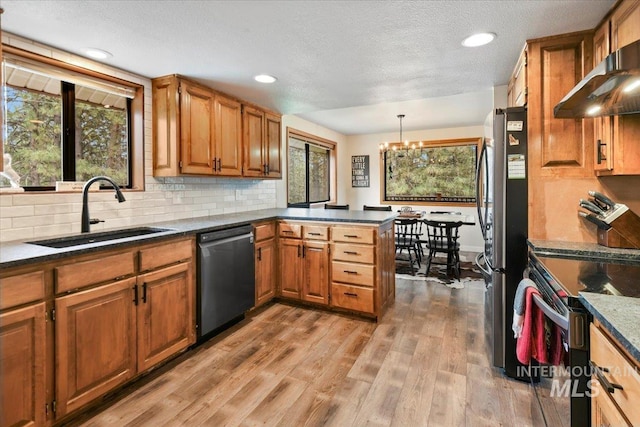 76 W Castle Creek Rd, Garden Valley, ID 83622 - kitchen featuring appliances with stainless steel finishes, a sink, wall chimney range hood, a peninsula, and a chandelier