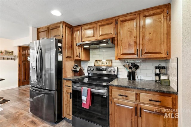 76 W Castle Creek Rd, Garden Valley, ID 83622 - kitchen featuring stainless steel appliances, under cabinet range hood, tasteful backsplash, light wood-style flooring, and brown cabinets