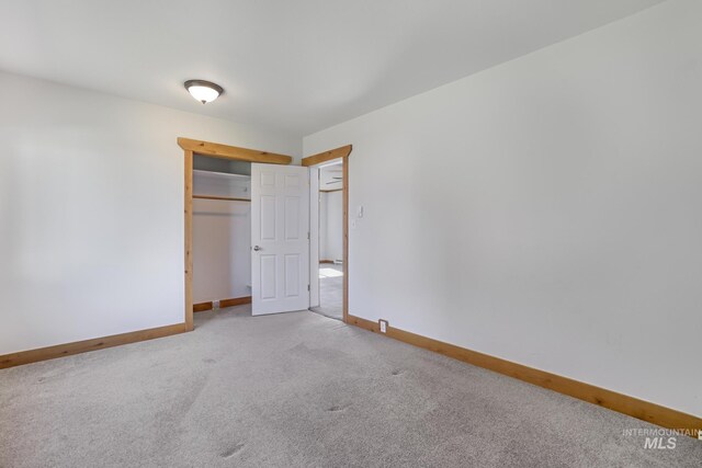 unfurnished bedroom featuring a closet, baseboards, and light colored carpet