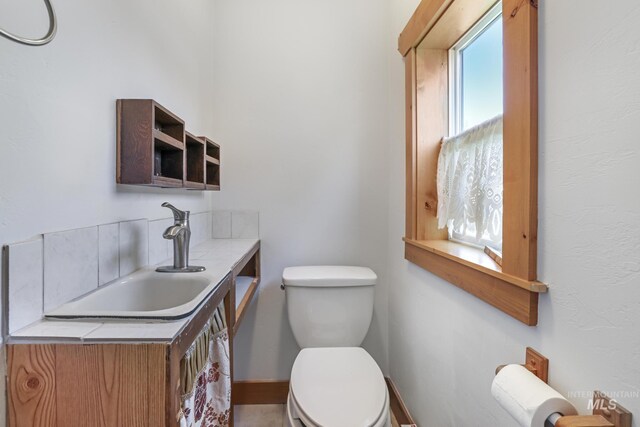 half bathroom featuring baseboards, vanity, and toilet