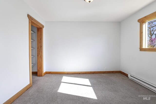 spare room featuring a baseboard heating unit, baseboards, and carpet floors