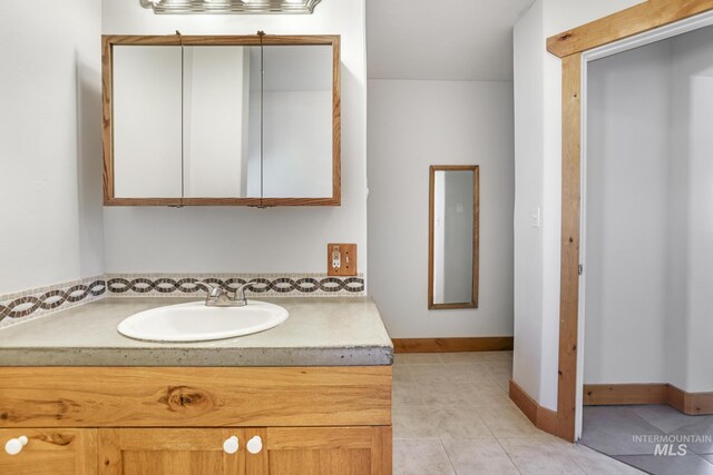 bathroom with baseboards, tile patterned flooring, and vanity