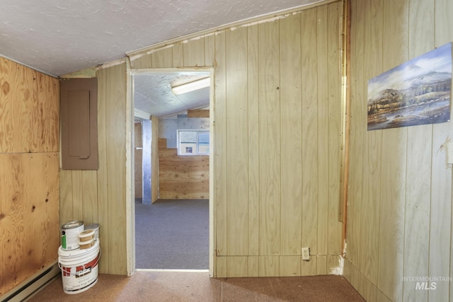 hallway with lofted ceiling, wood walls, electric panel, a baseboard radiator, and carpet flooring