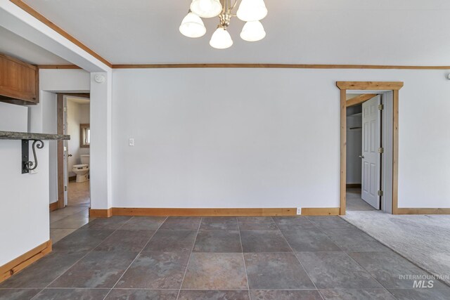 empty room with baseboards and an inviting chandelier