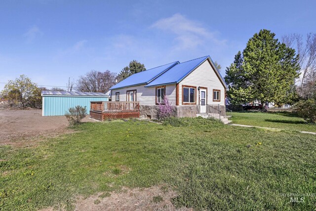 view of front of house featuring a wooden deck, a front lawn, and metal roof