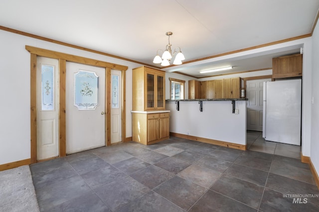 kitchen featuring glass insert cabinets, baseboards, a notable chandelier, and freestanding refrigerator