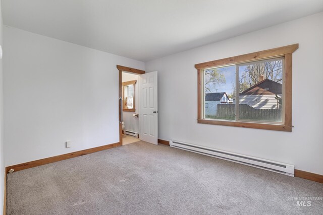 empty room featuring baseboard heating, baseboards, and carpet