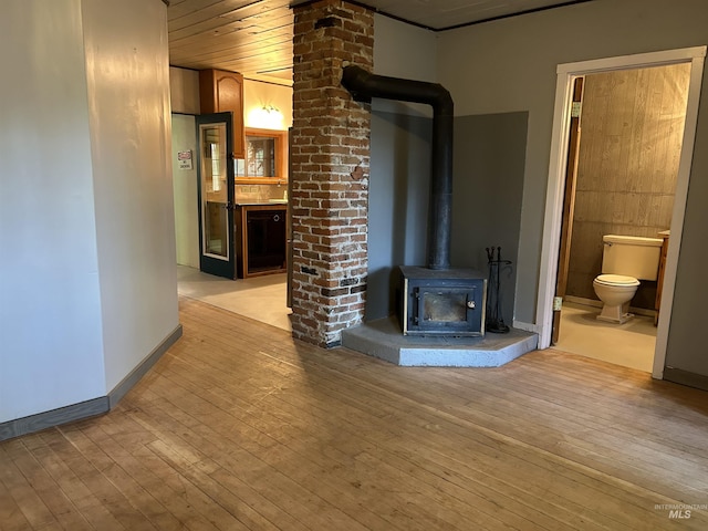 unfurnished living room featuring a wood stove and light wood-type flooring