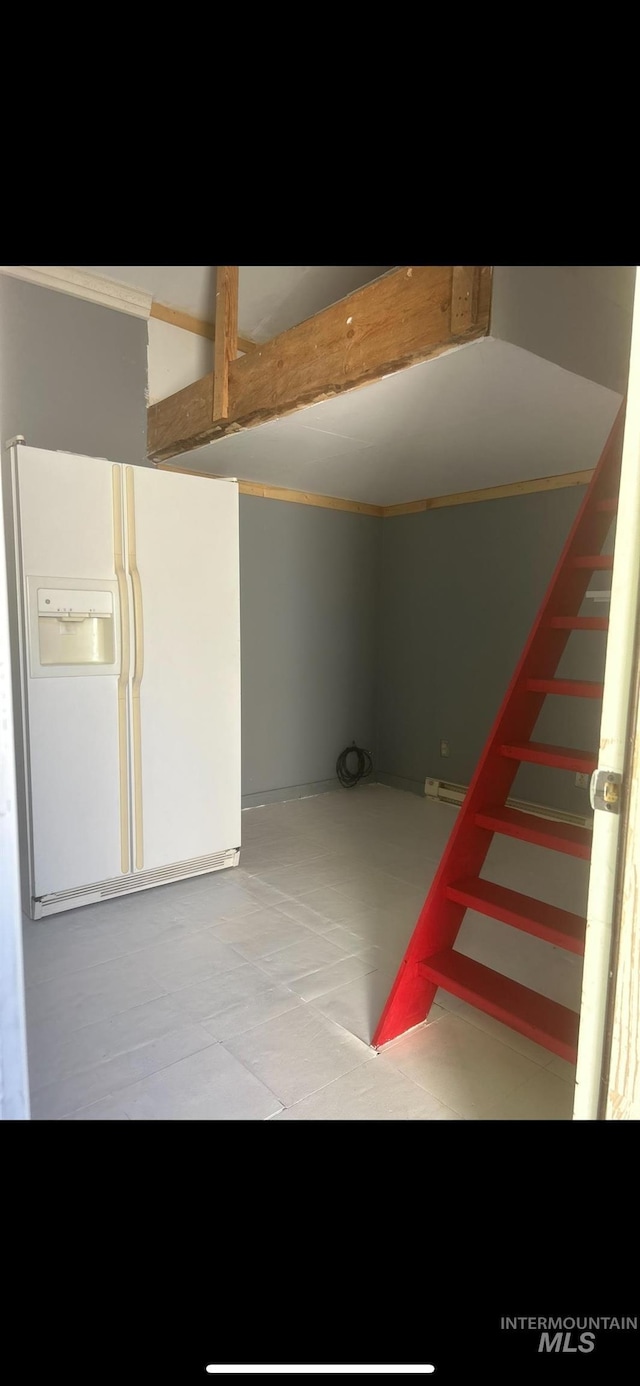 basement featuring white refrigerator with ice dispenser