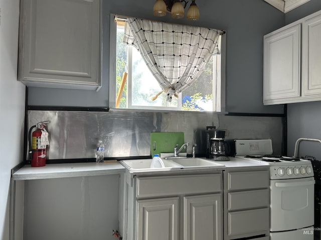 kitchen with sink, white gas range oven, white cabinetry, tasteful backsplash, and a healthy amount of sunlight