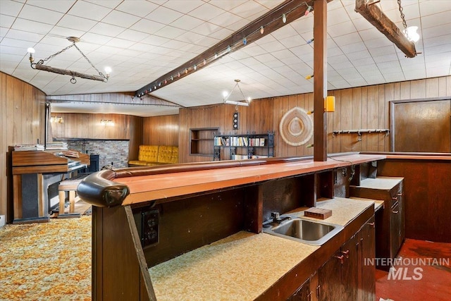 kitchen featuring carpet floors, vaulted ceiling, a sink, and wooden walls