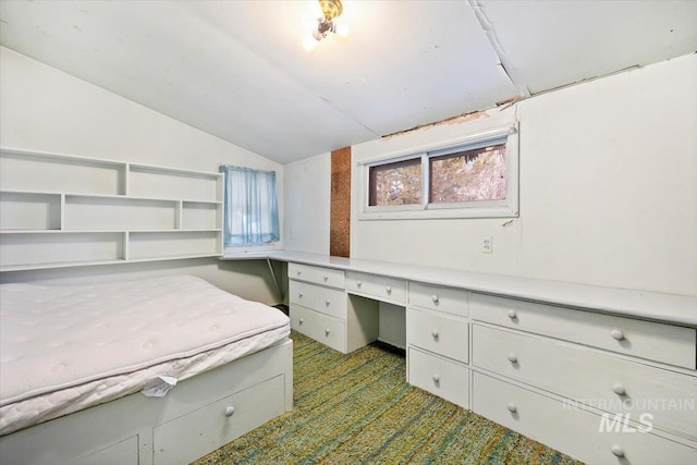 unfurnished office featuring lofted ceiling, carpet, and built in study area