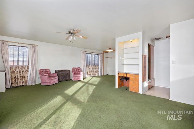 interior space with carpet floors, built in shelves, and a ceiling fan