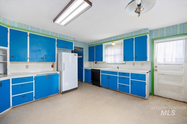 kitchen featuring blue cabinets, black dishwasher, light countertops, freestanding refrigerator, and wallpapered walls