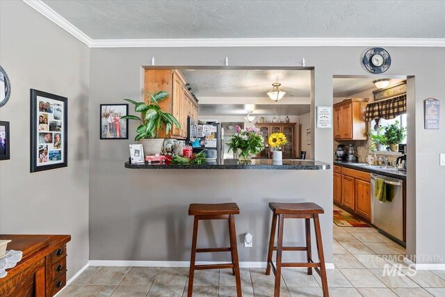 705 H St, Rupert, ID 83350 - kitchen featuring a peninsula, a kitchen breakfast bar, light tile patterned floors, dark countertops, and appliances with stainless steel finishes
