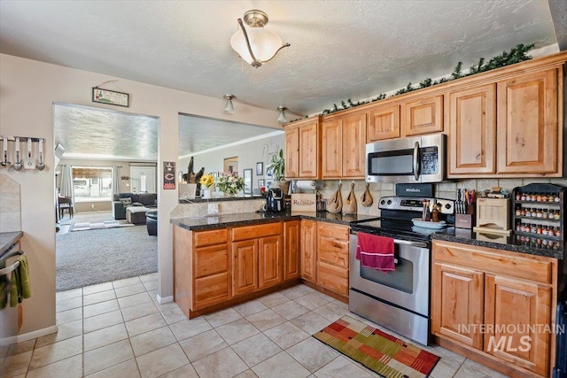705 H St, Rupert, ID 83350 - kitchen featuring a peninsula, light colored carpet, light tile patterned flooring, decorative backsplash, and appliances with stainless steel finishes
