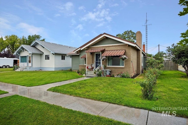 705 H St, Rupert, ID 83350 - bungalow-style home featuring a chimney, brick siding, a front lawn, and fence