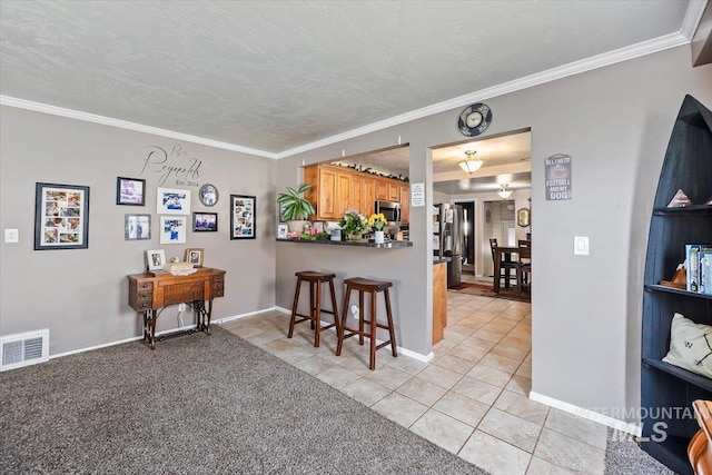 705 H St, Rupert, ID 83350 - kitchen featuring a breakfast bar area, light tile patterned floors, visible vents, stainless steel microwave, and ornamental molding