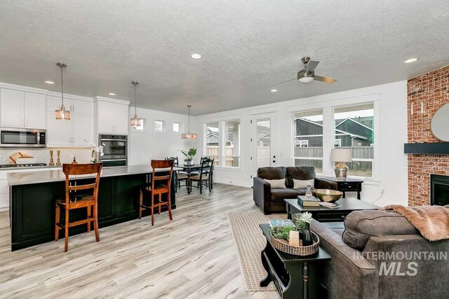 living room featuring a wealth of natural light, a textured ceiling, light wood-type flooring, and a fireplace