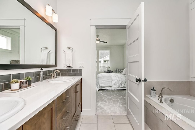 bathroom with tiled tub, vanity, tile patterned floors, and ceiling fan